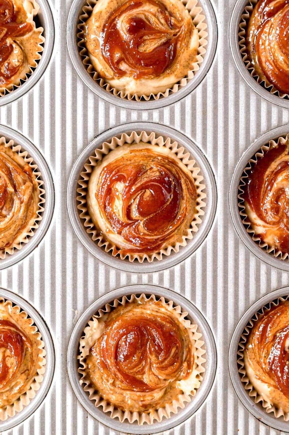 almond butter and guava jelly swirled on top of muffins in muffin pan before baking
