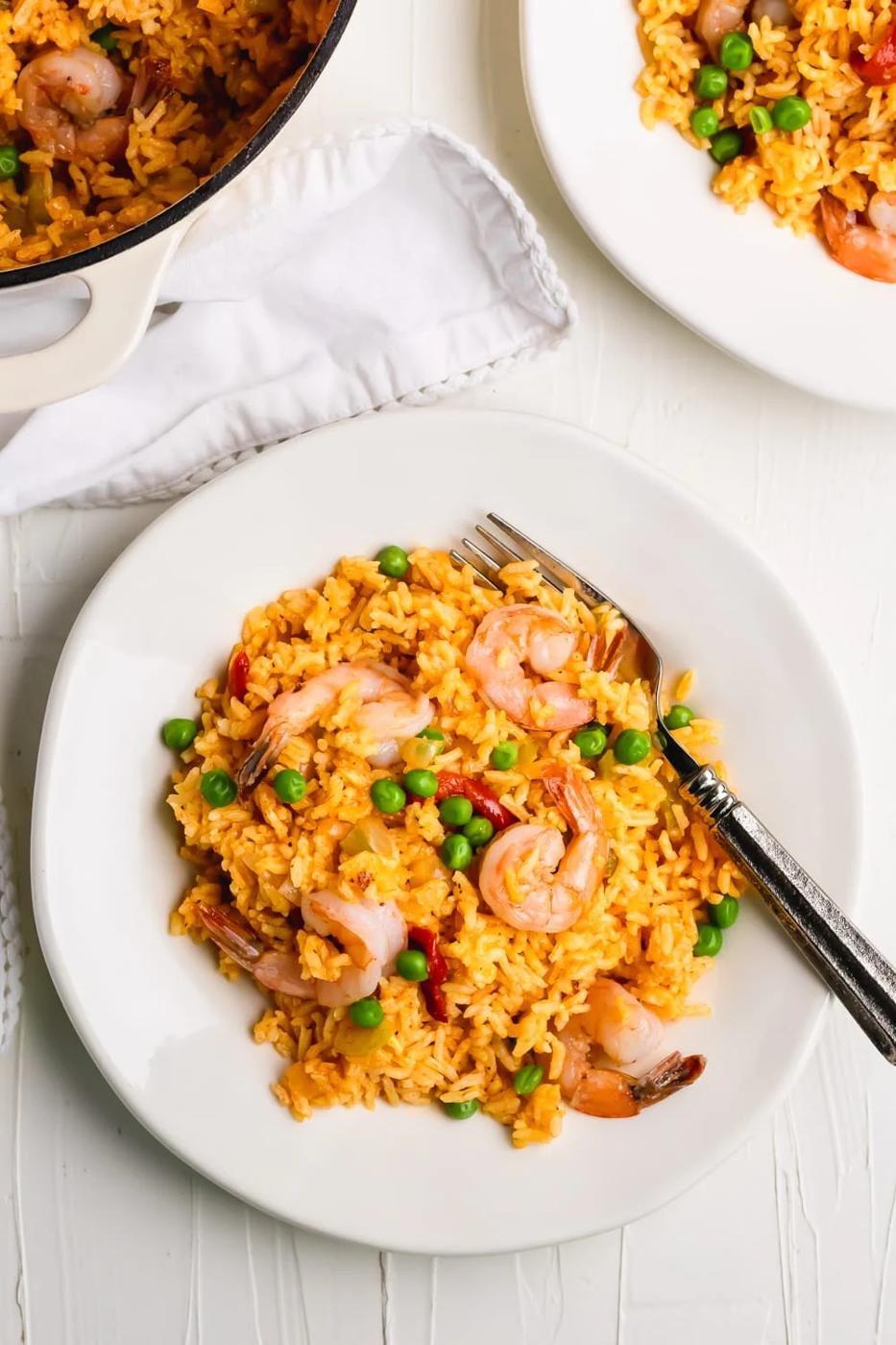 yellow rice with shrimp on a white plate on a white table