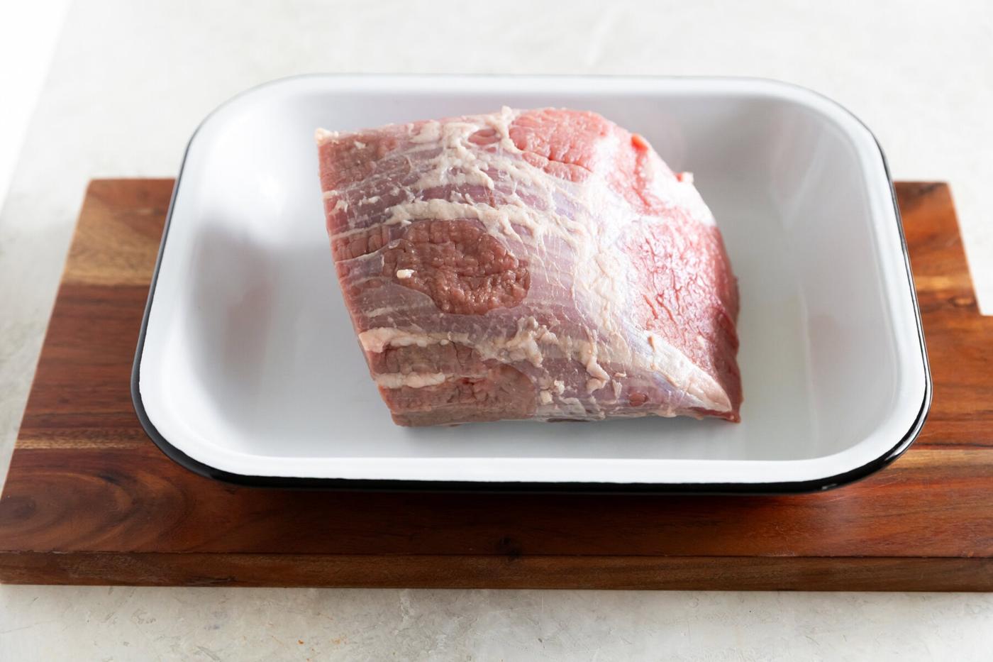 Raw beef brisket for cooking or BBQ on a white dish.
