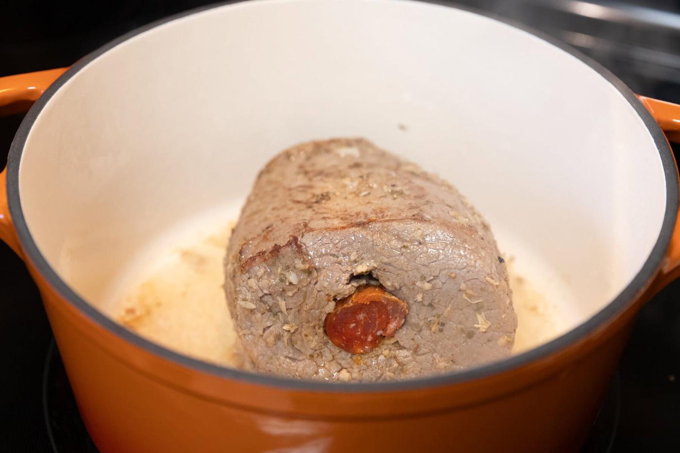 Savory meatloaf cooking in a Dutch oven with a tomato center.