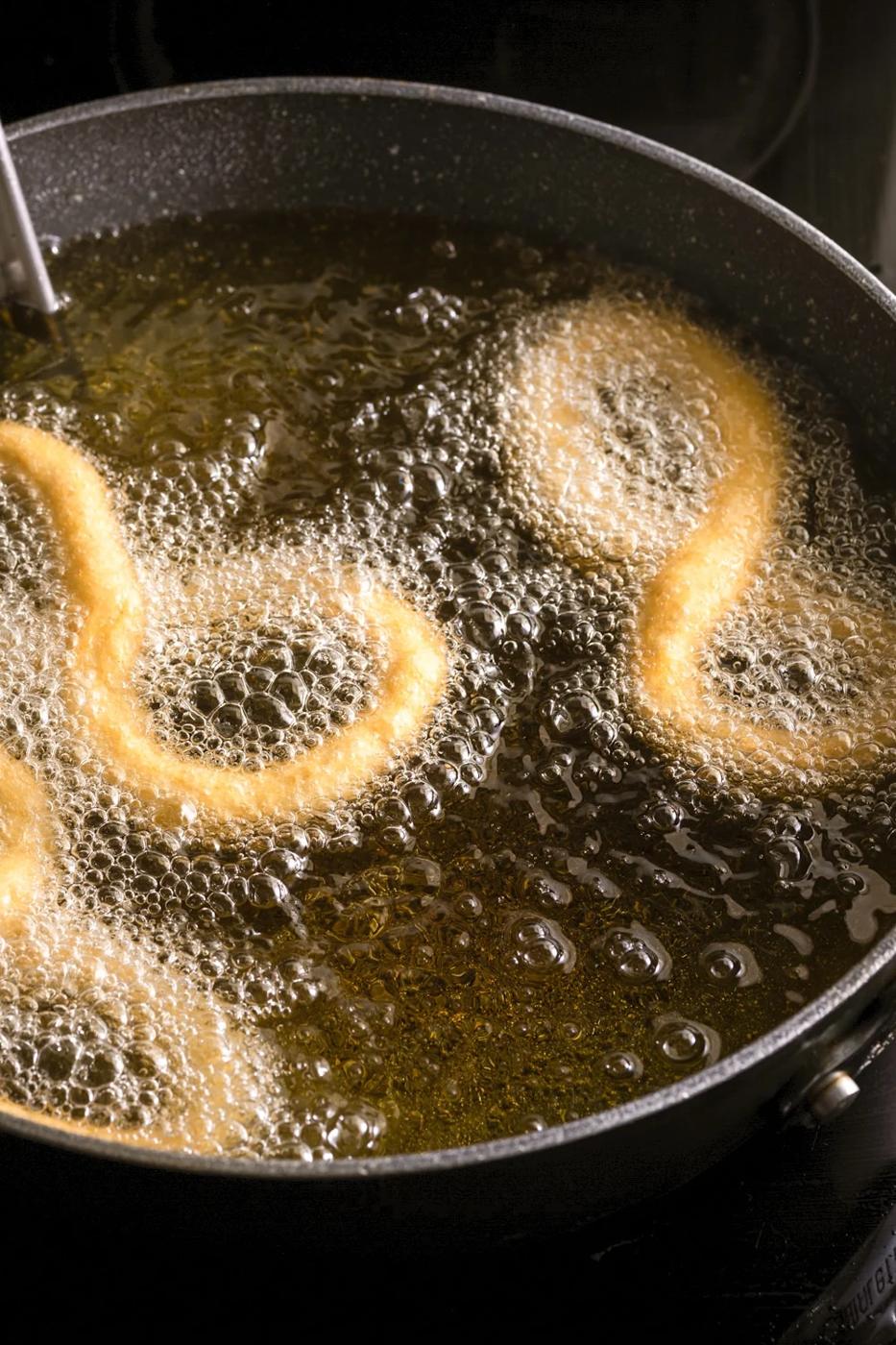 Cuban bunuelos frying in oil in a saucepan