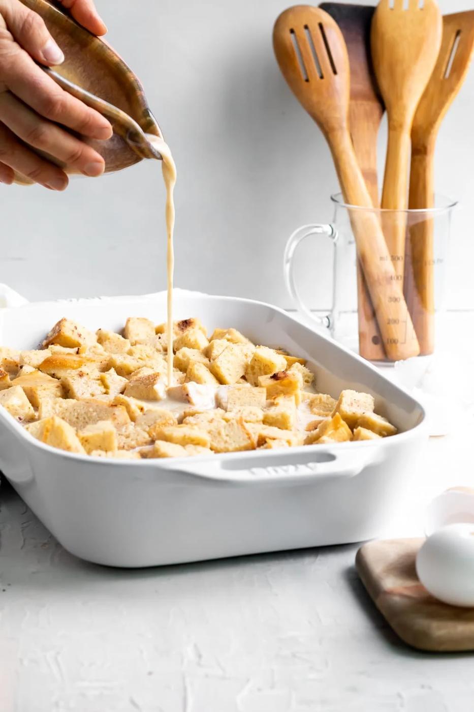 pouring the custard mixture over the bread cubes