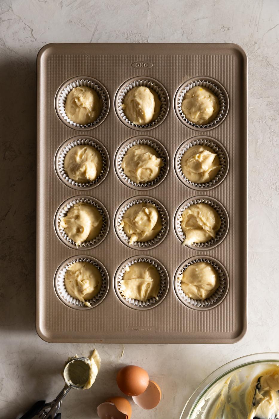 Mini cheesecake batter in muffin tin for dessert baking.
