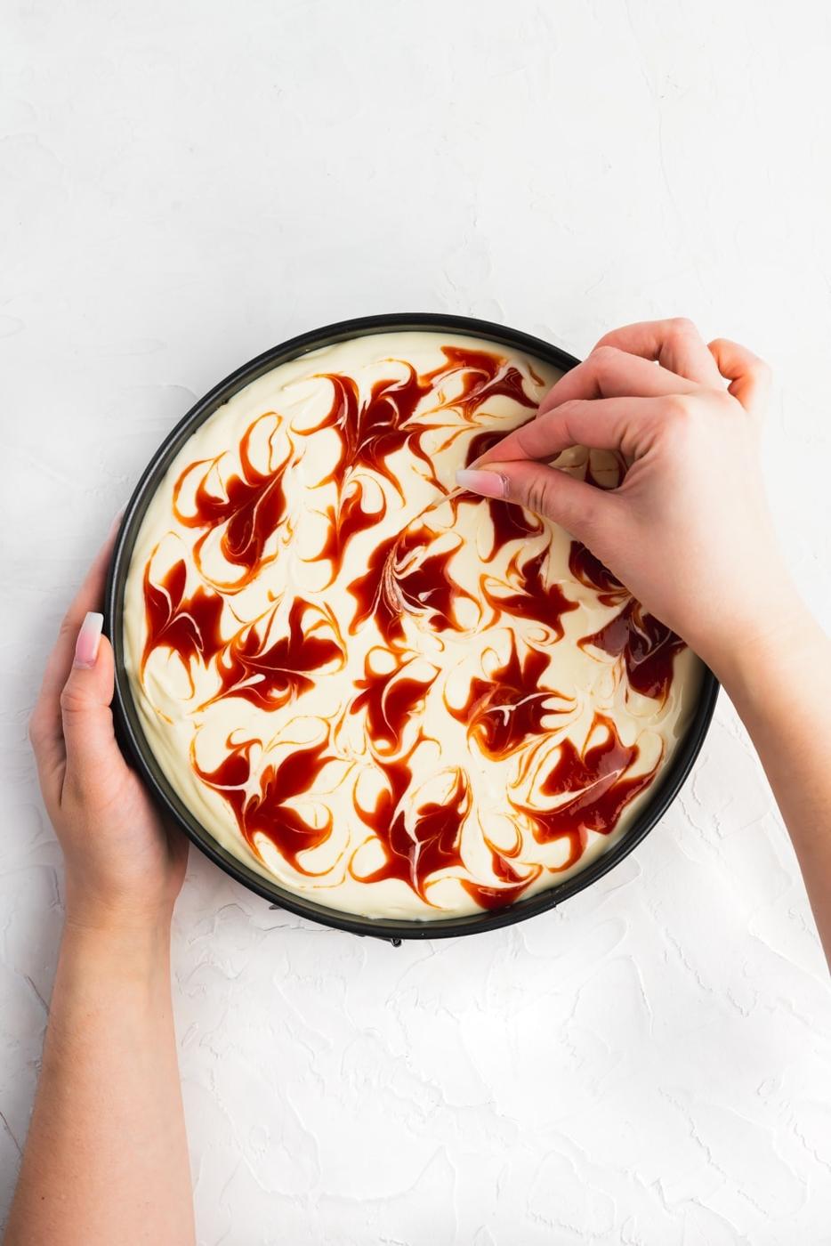 cheesecake mixture in springform pan with guava marmalade swirls on top
