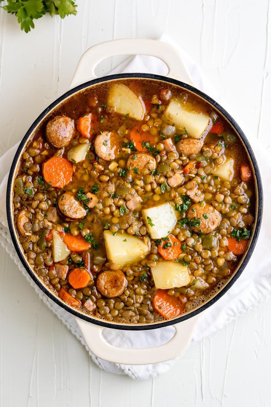 Cuban lentil soup in a Dutch oven with potatoes, chorizo, smoked ham, carrots, sofrito and spices.