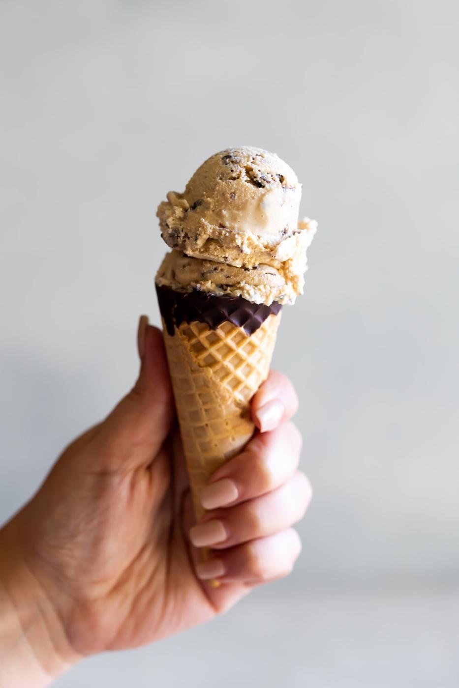 hand holding sugar cone with salted caramel ice cream