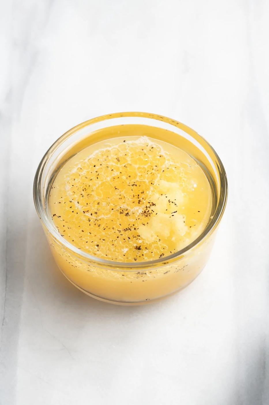 garlic mojo dipping sauce in a clear bowl on a marble slab