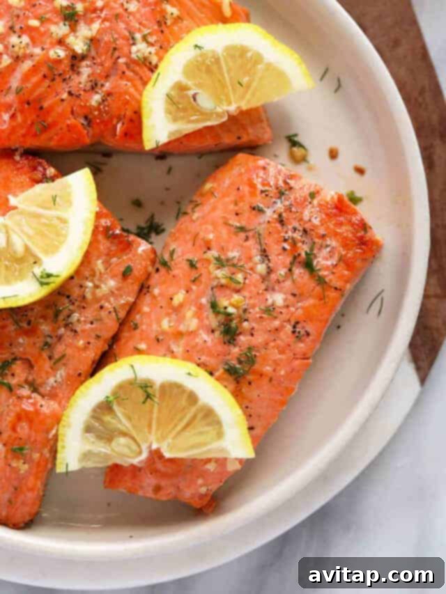 Perfectly pan-seared salmon with a glistening lemon butter sauce on a plate, garnished with fresh dill and lemon slices.