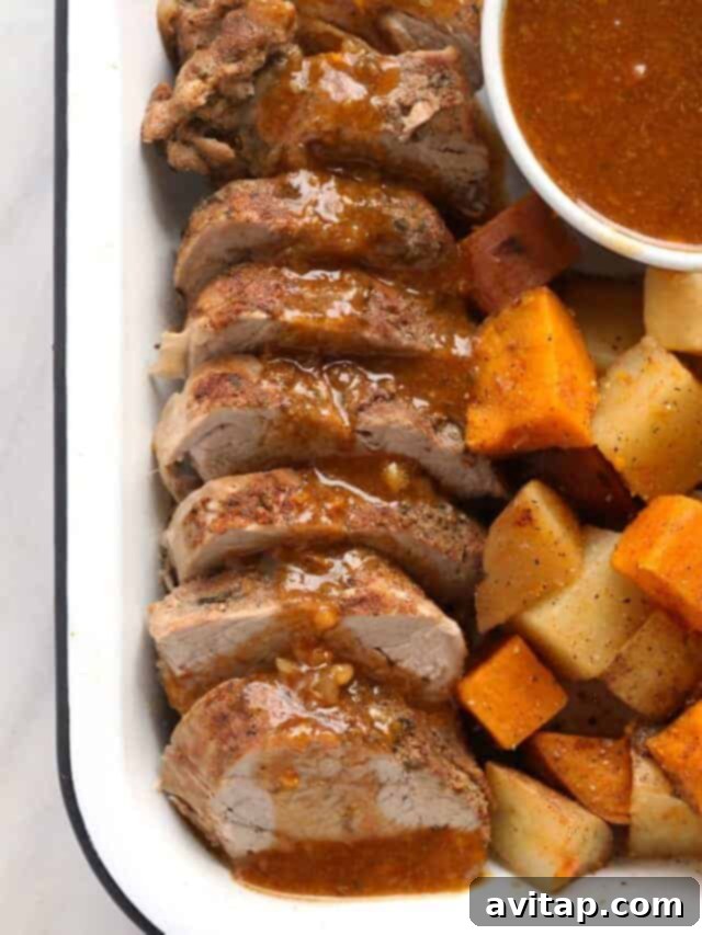 Perfectly sliced Instant Pot pork tenderloin with a rich sauce on a platter, garnished with fresh rosemary.
