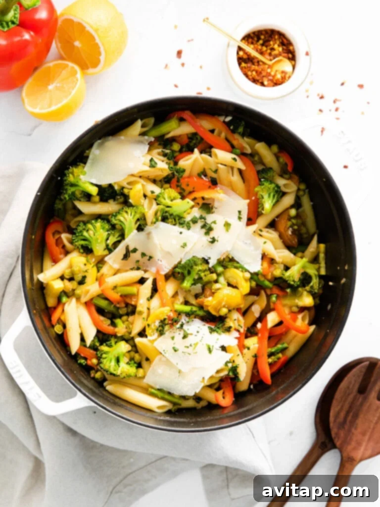 A large bowl of colorful 30-minute pasta primavera featuring whole wheat pasta, an array of fresh vegetables, and crispy bacon bits.
