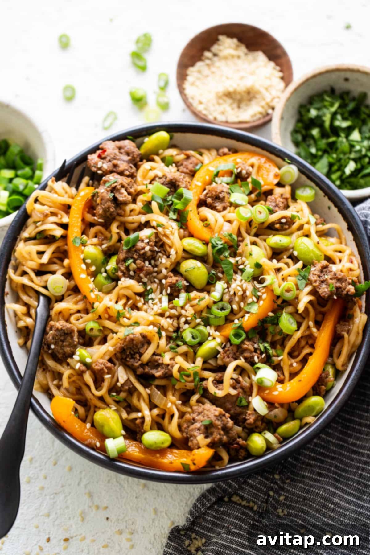 A steaming bowl of one-pot ground beef ramen noodles with colorful vegetables, tender beef, and a savory broth, garnished with fresh herbs.