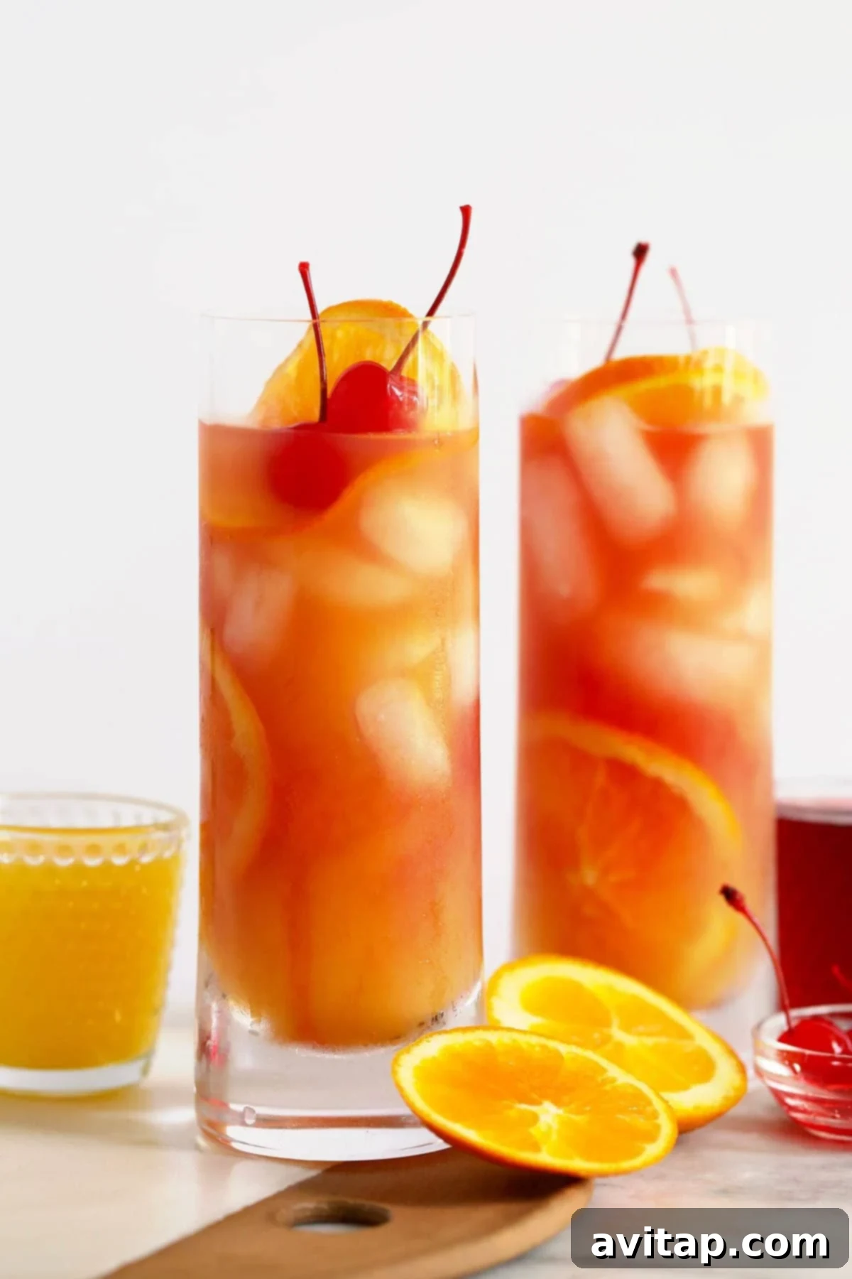Two Sex on the Beach cocktails beautifully garnished with orange slices and maraschino cherries, set against a bright, inviting background.