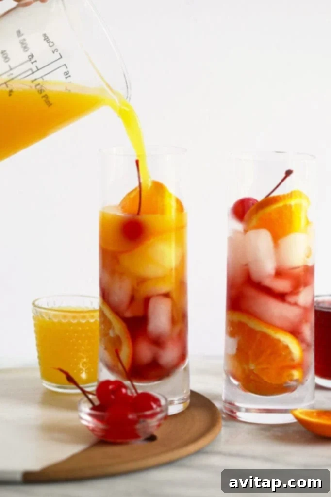 Orange juice being carefully poured into a glass to create a layered Sex on the Beach cocktail, highlighting the vibrant colors.