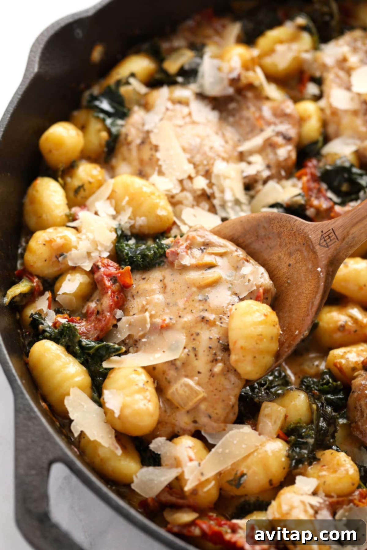 A mouthwatering Creamy Tuscan Chicken and Gnocchi dish in a rustic cast iron skillet, garnished with fresh herbs and parmesan.