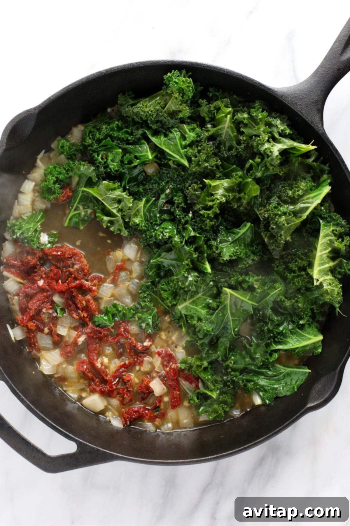 Freshly sautéed white onions and minced garlic in butter, forming the aromatic base for the creamy Tuscan sauce in a cast iron skillet.