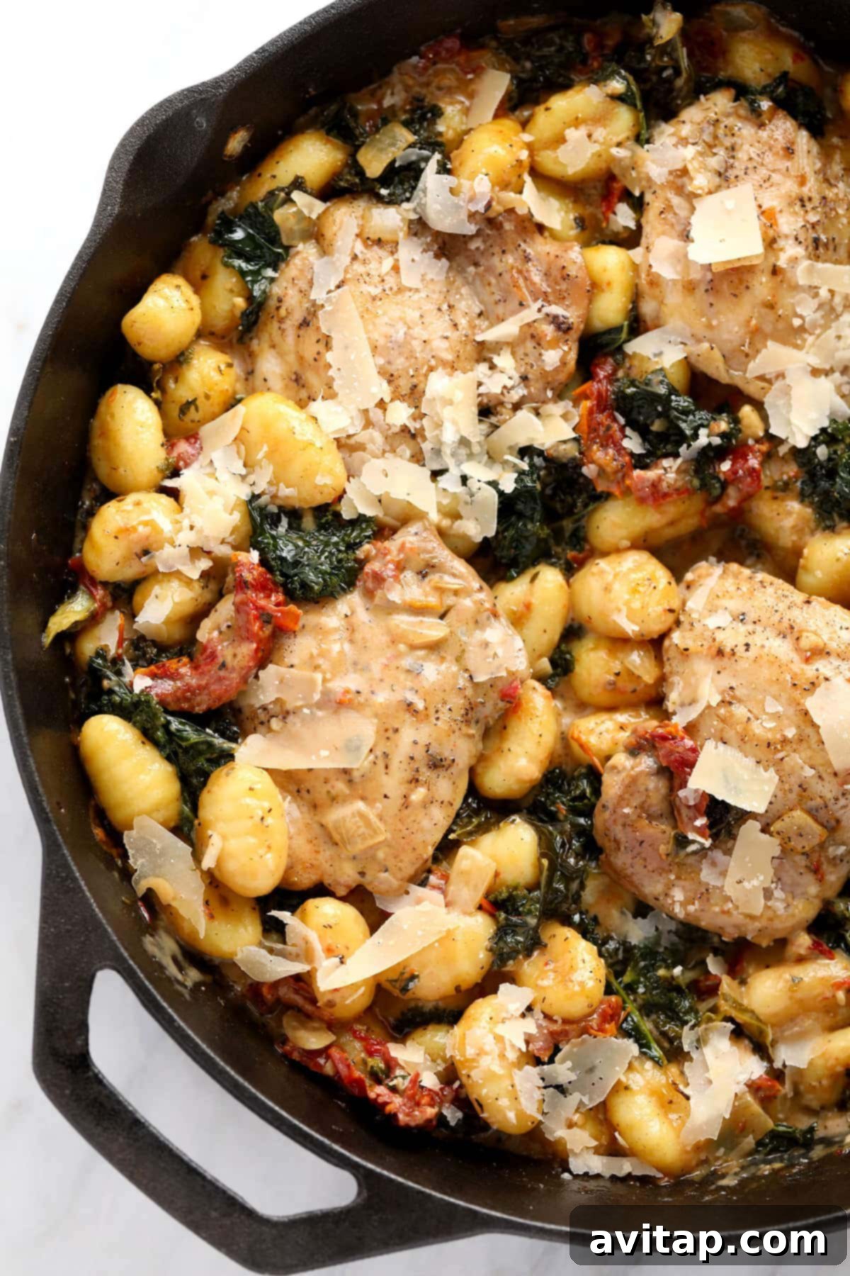 A delicious Creamy Tuscan Chicken and Gnocchi, presented in a cast iron skillet, ready to be dished out and enjoyed as a satisfying meal.