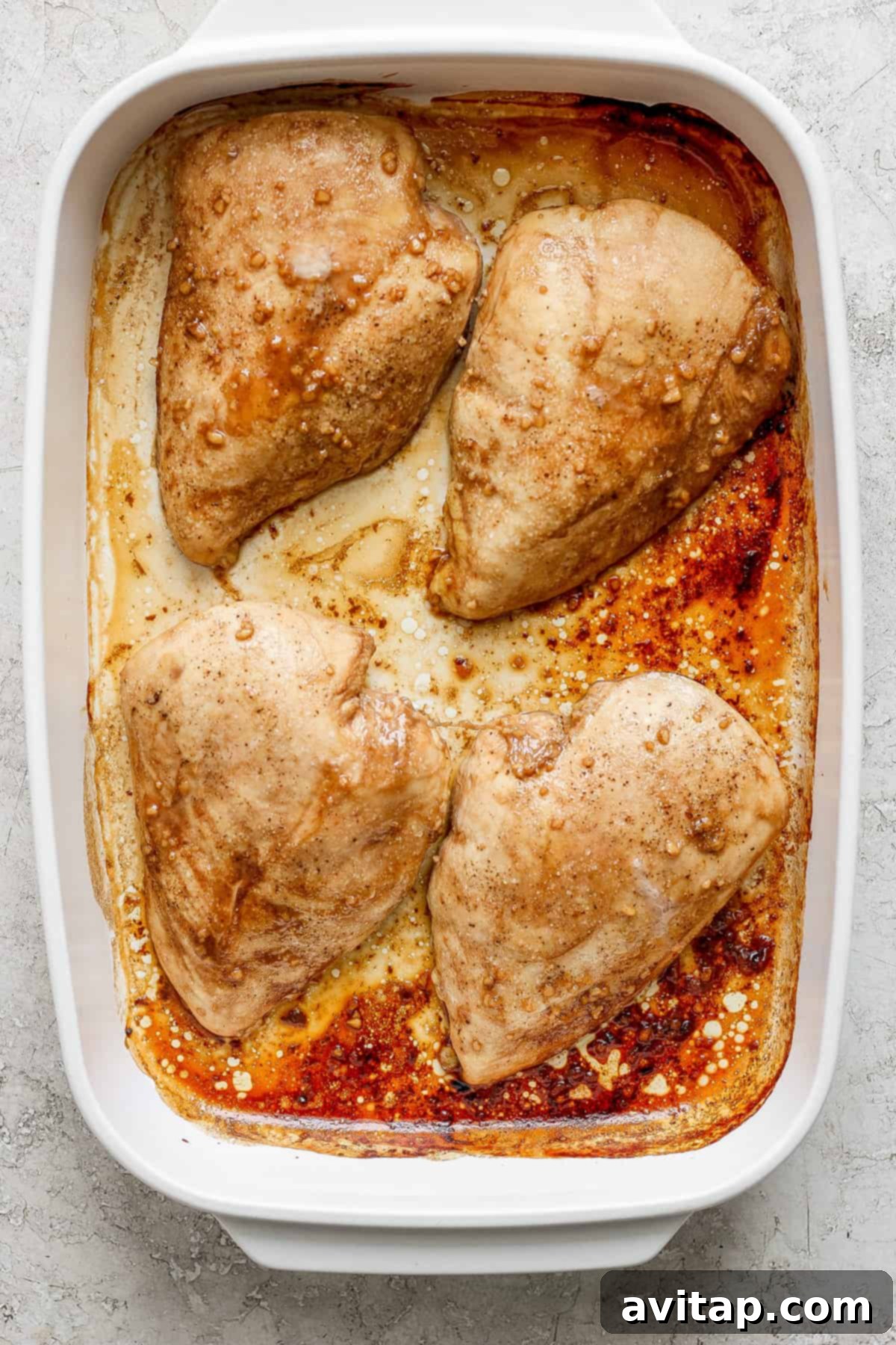 Raw chicken breasts marinating in a dish.