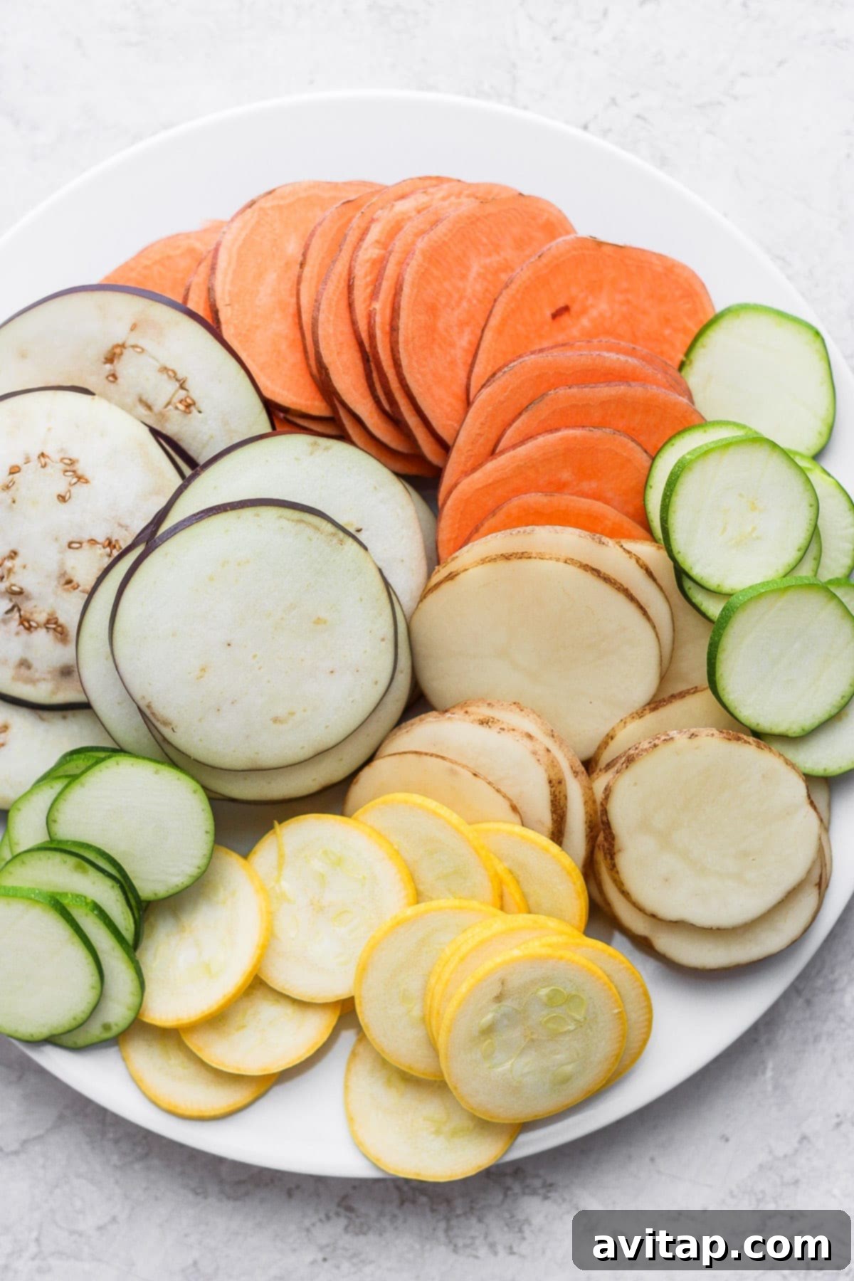 Assorted root vegetables and squashes on a cutting board, prepped for slicing into rounds.