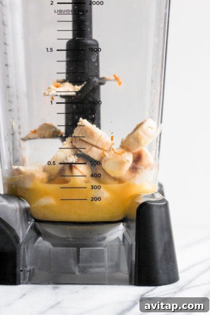 Blending the Perfect Orange Creamsicle Smoothie Orange creamsicle smoothie being blended in a high-speed blender, creating a smooth, frothy texture.