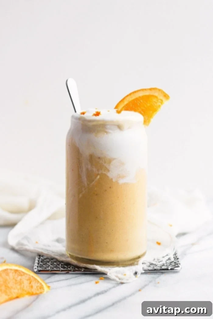 Garnished Orange Creamsicle Smoothie Refreshing Orange Creamsicle Smoothie in a clear glass, garnished with a fresh orange slice and mint leaves, ready to be enjoyed.