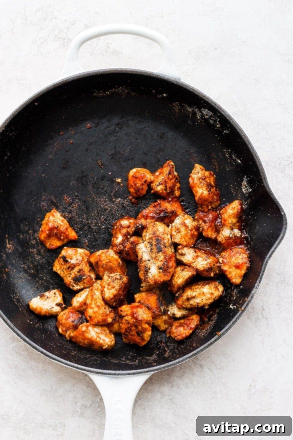 Diced chicken pieces browning in a skillet, developing a crispy texture.