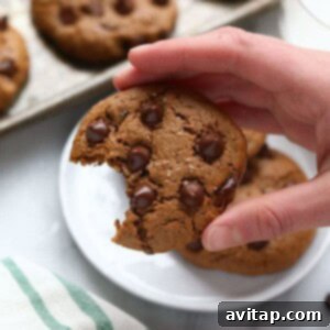 A hand holding a paleo cashew butter cookie with a bite taken out of it, showcasing its delicious texture.