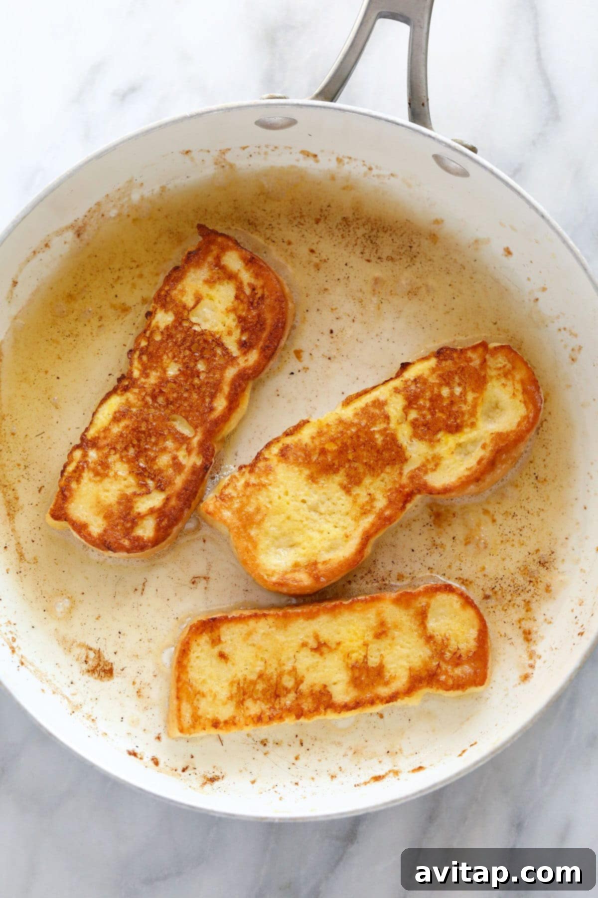 Frying French Toast Sticks to Golden Perfection French Toast Sticks cooking beautifully in a non-stick pan until they are perfectly golden brown and slightly crispy.