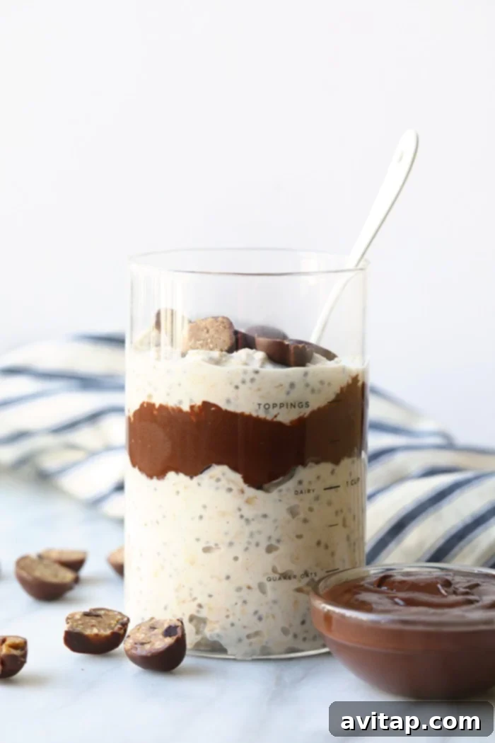 Overnight oatmeal in a jar, beautifully layered with a fudge swirl and visible cookie dough chunks, ready for breakfast.