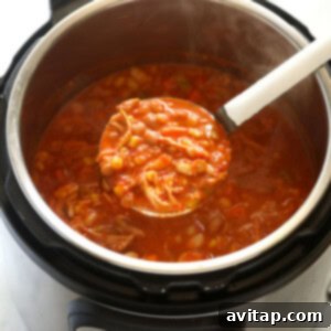 An Instant Pot full of buffalo chicken chili with a spoon in it, showing the final creamy consistency after adding Greek yogurt.