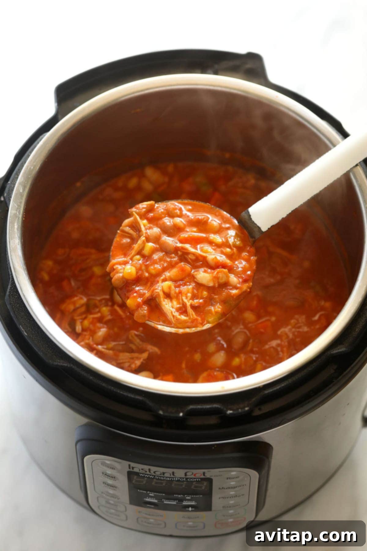 Close-up of the buffalo chicken chili in the Instant Pot, with a spoon stirring, showing its rich texture and steam.