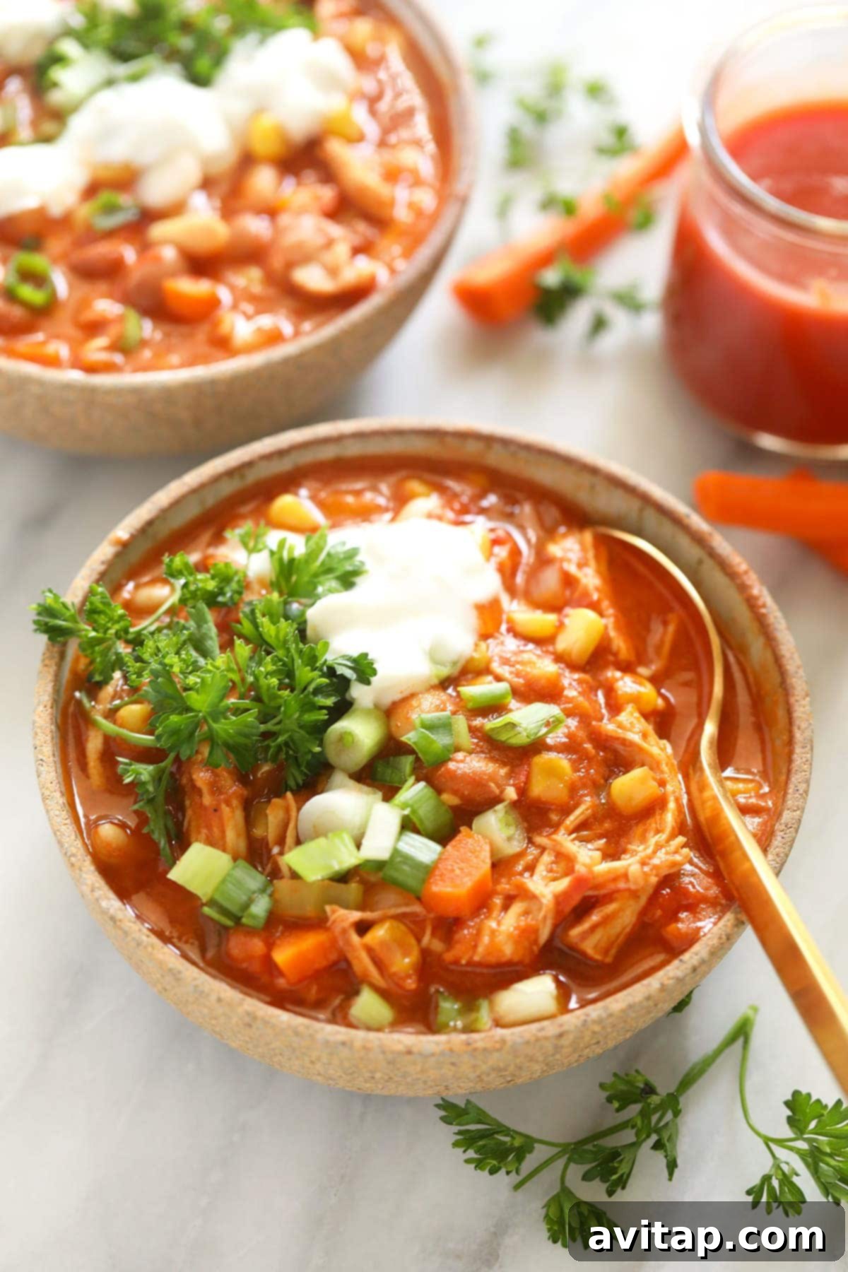 A beautifully presented bowl of buffalo chicken chili, topped with sour cream or Greek yogurt and fresh green onions, ready to eat.