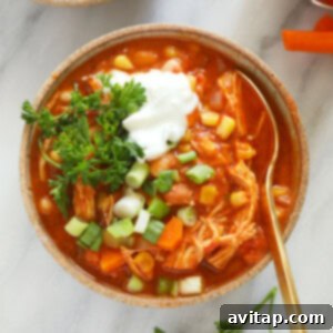 A bowl of buffalo chicken chili with sour cream, carrots, and green onions.