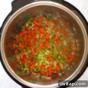 An instant pot filled with chopped veggies being sautéed.
