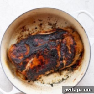 A perfectly seared pork roast in a cast iron pan, showcasing its crispy, golden-brown crust before being placed in the oven.