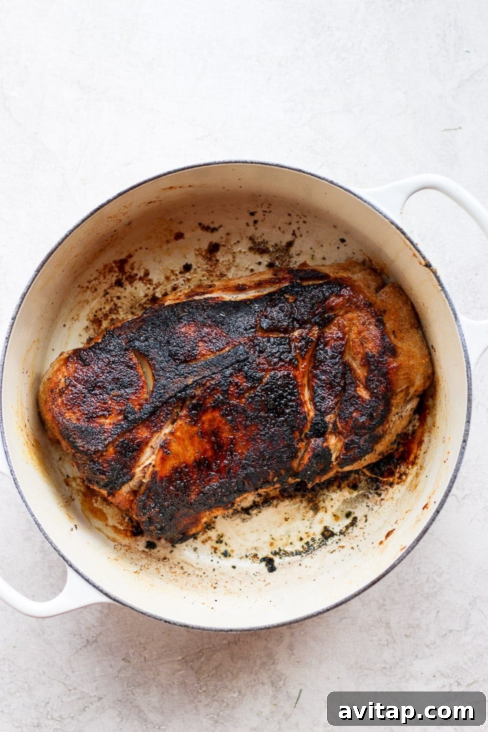 Searing the pork shoulder is a vital first step, creating a flavorful crust before oven roasting. Expertly seared pork shoulder resting in a cast iron stock pot, showcasing its golden-brown crust, ready for further cooking.