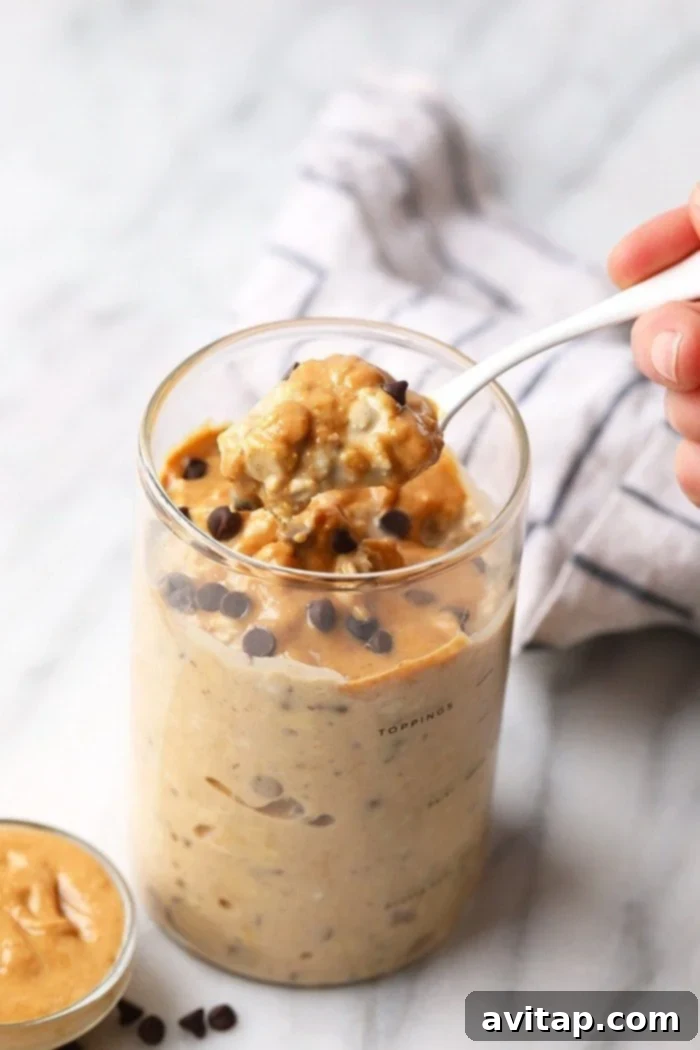 A spoon digging into a jar of creamy peanut butter cookie dough overnight oats.