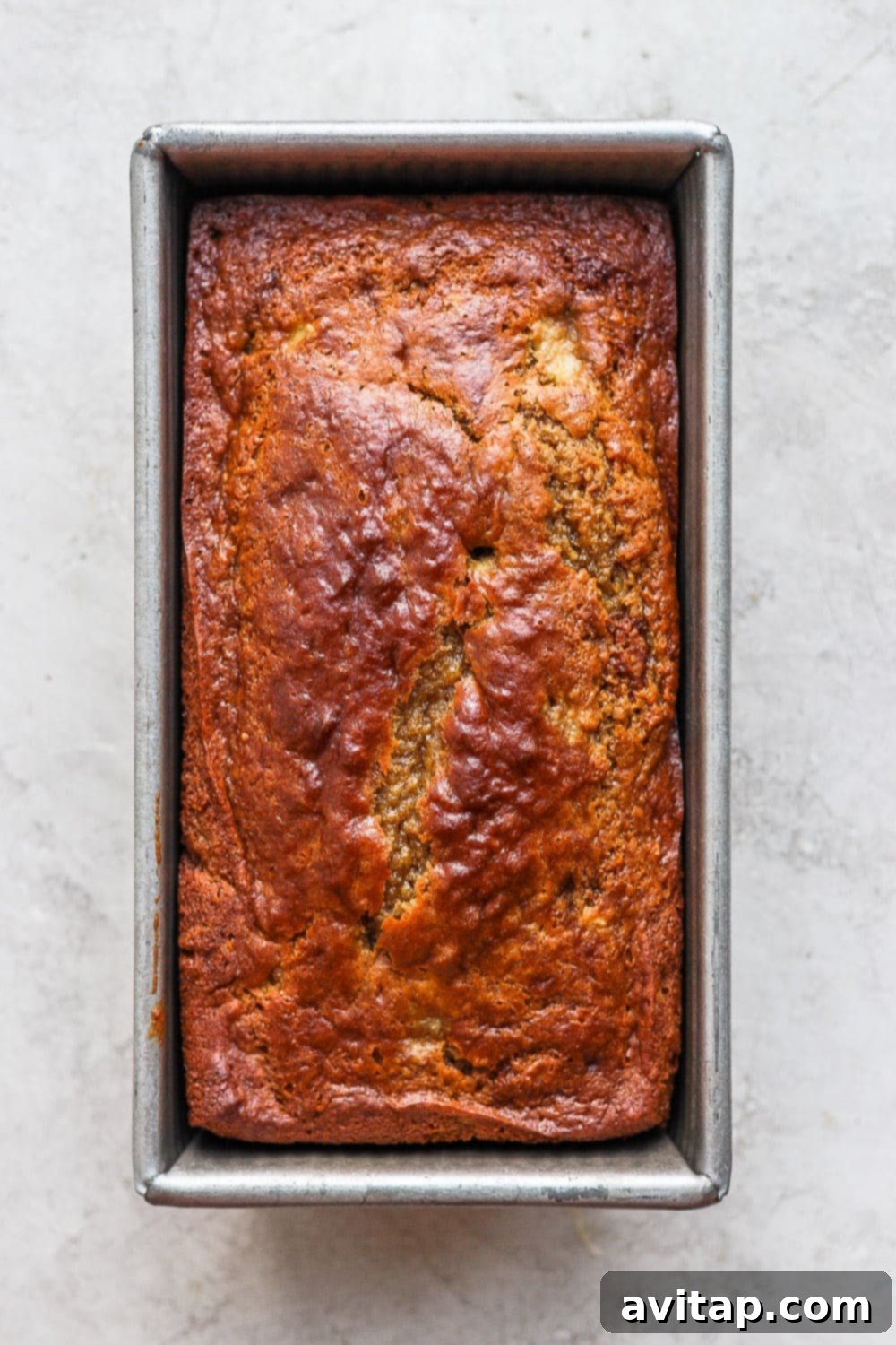 Freshly Baked Healthy Banana Bread in Loaf Pan: Golden Brown and Ready to Cool A golden-brown loaf of healthy banana bread baking in a loaf pan, almost ready to be removed from the oven.