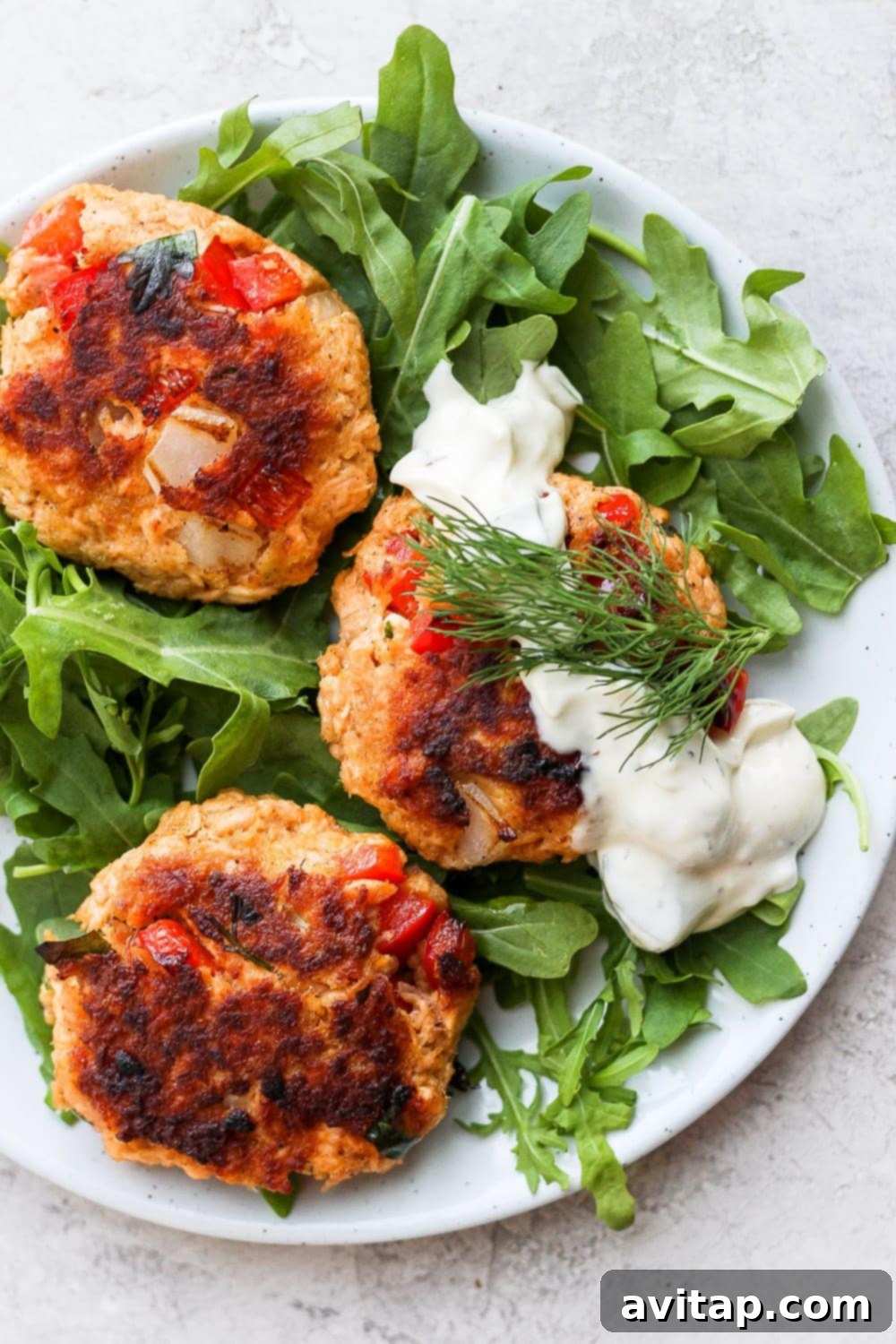 Easy Salmon Patties: Flakey, Crispy, and Healthy Crispy salmon patties served atop fresh arugula with a dollop of creamy tartar sauce