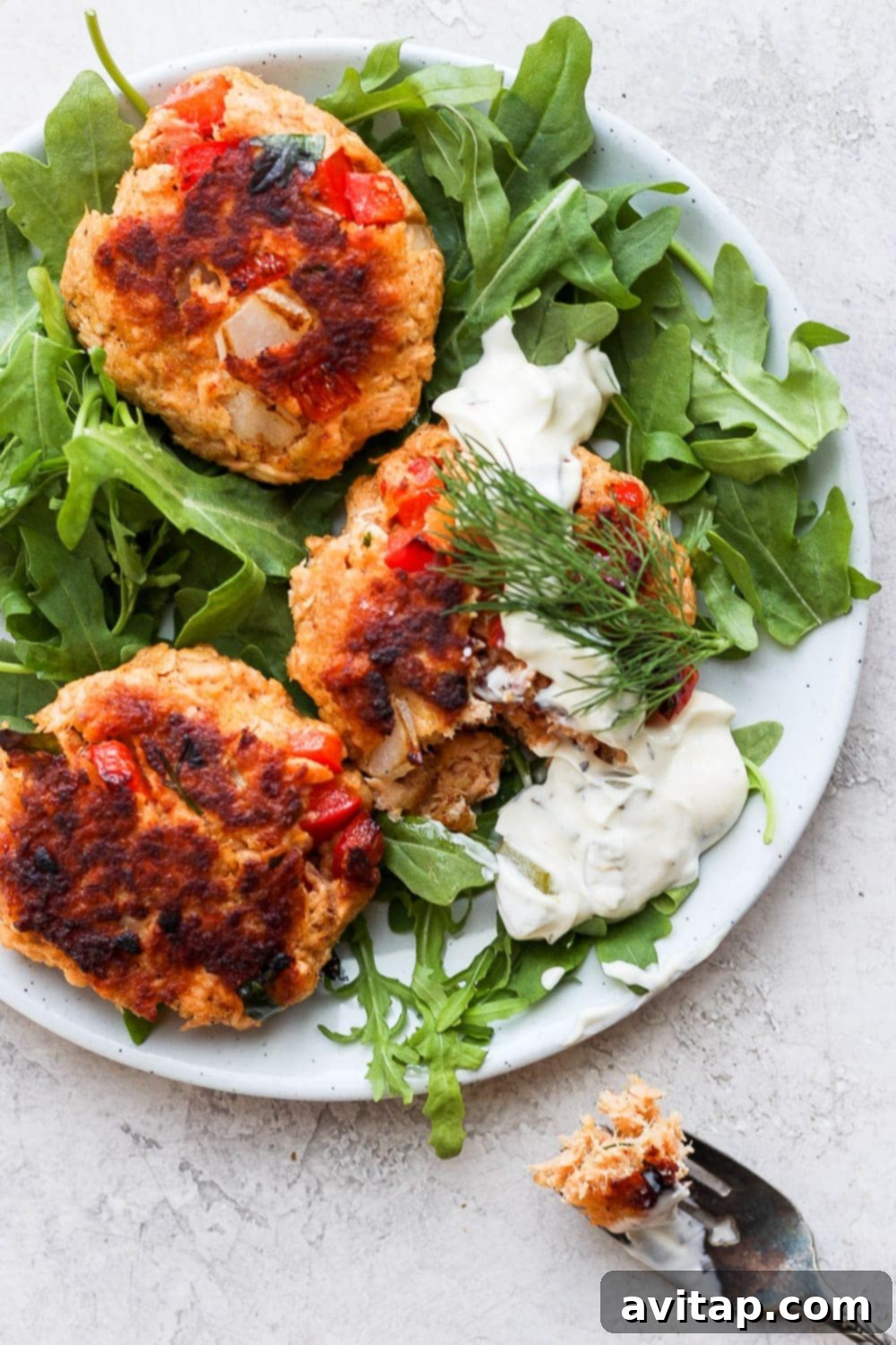 Plated Salmon Patties with Arugula Two perfectly cooked salmon patties served on a bed of fresh arugula