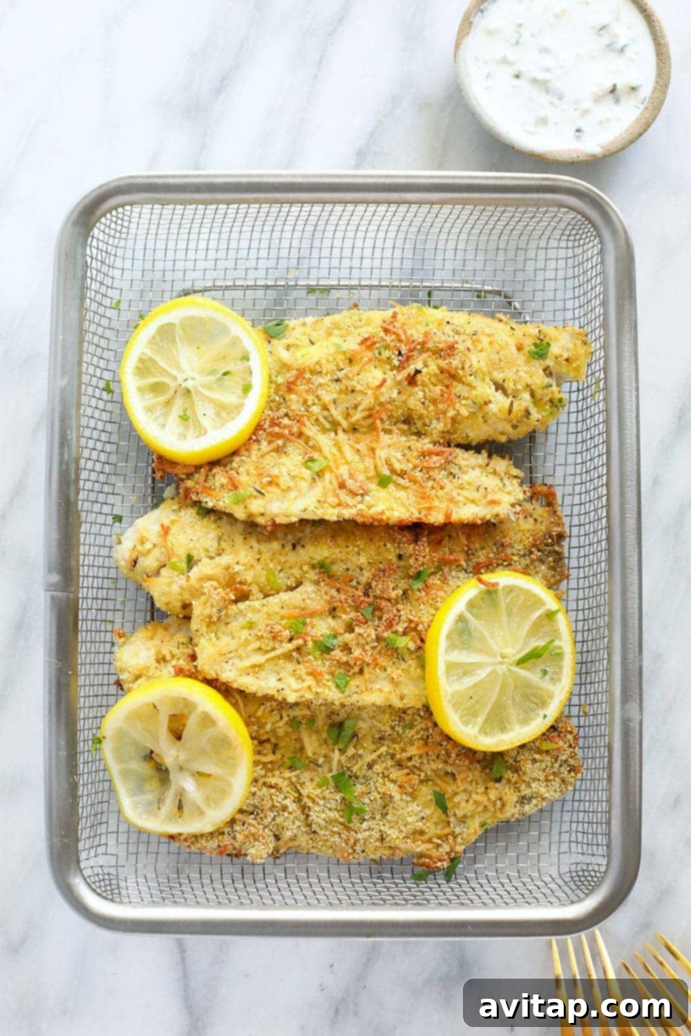 Baked tilapia in a basket, showcasing its golden, crispy Parmesan crust, garnished with fresh lemon.