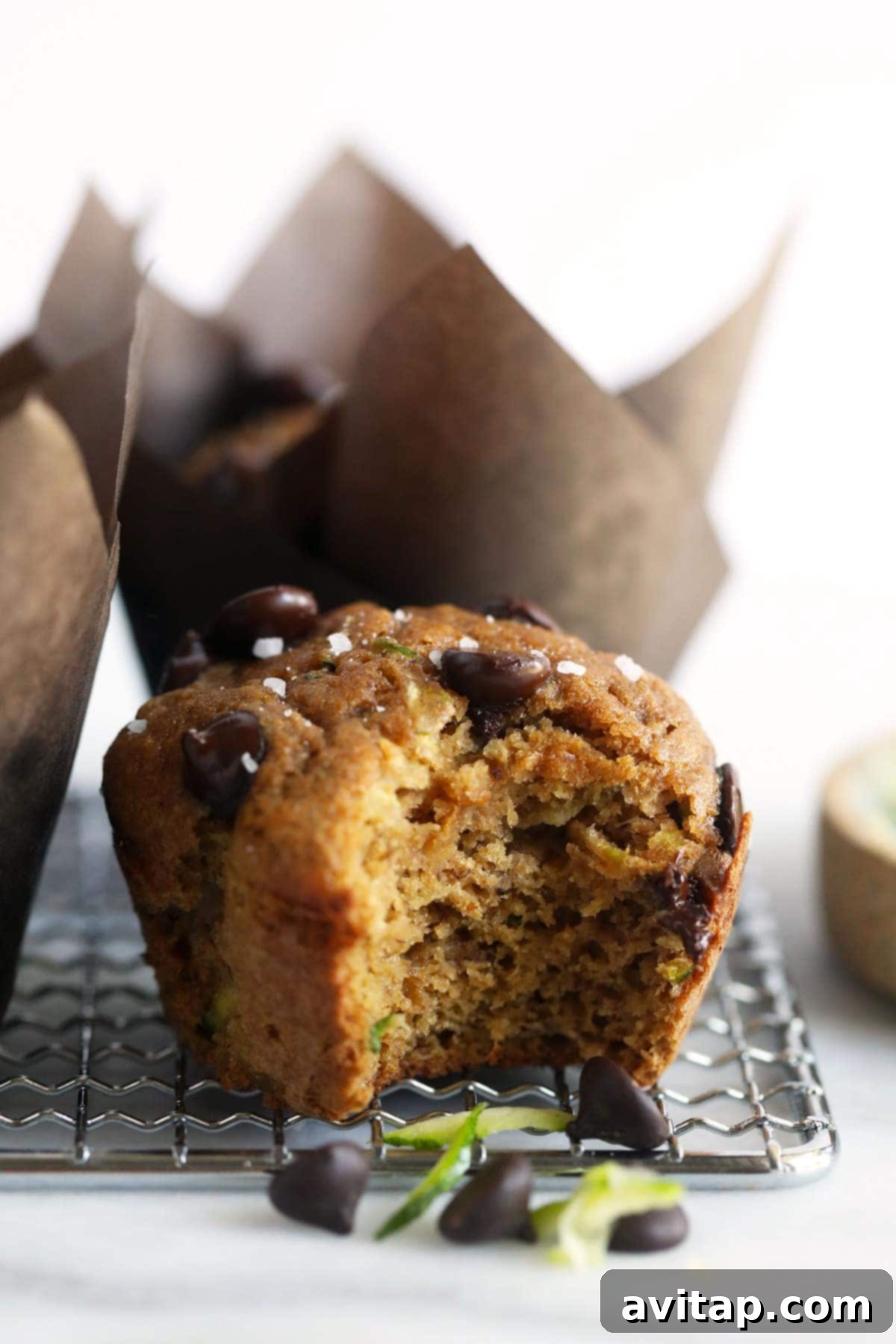 Effortless One-Bowl Zucchini Muffins 5 A delicious banana zucchini muffin with a bite taken out, revealing its moist interior.