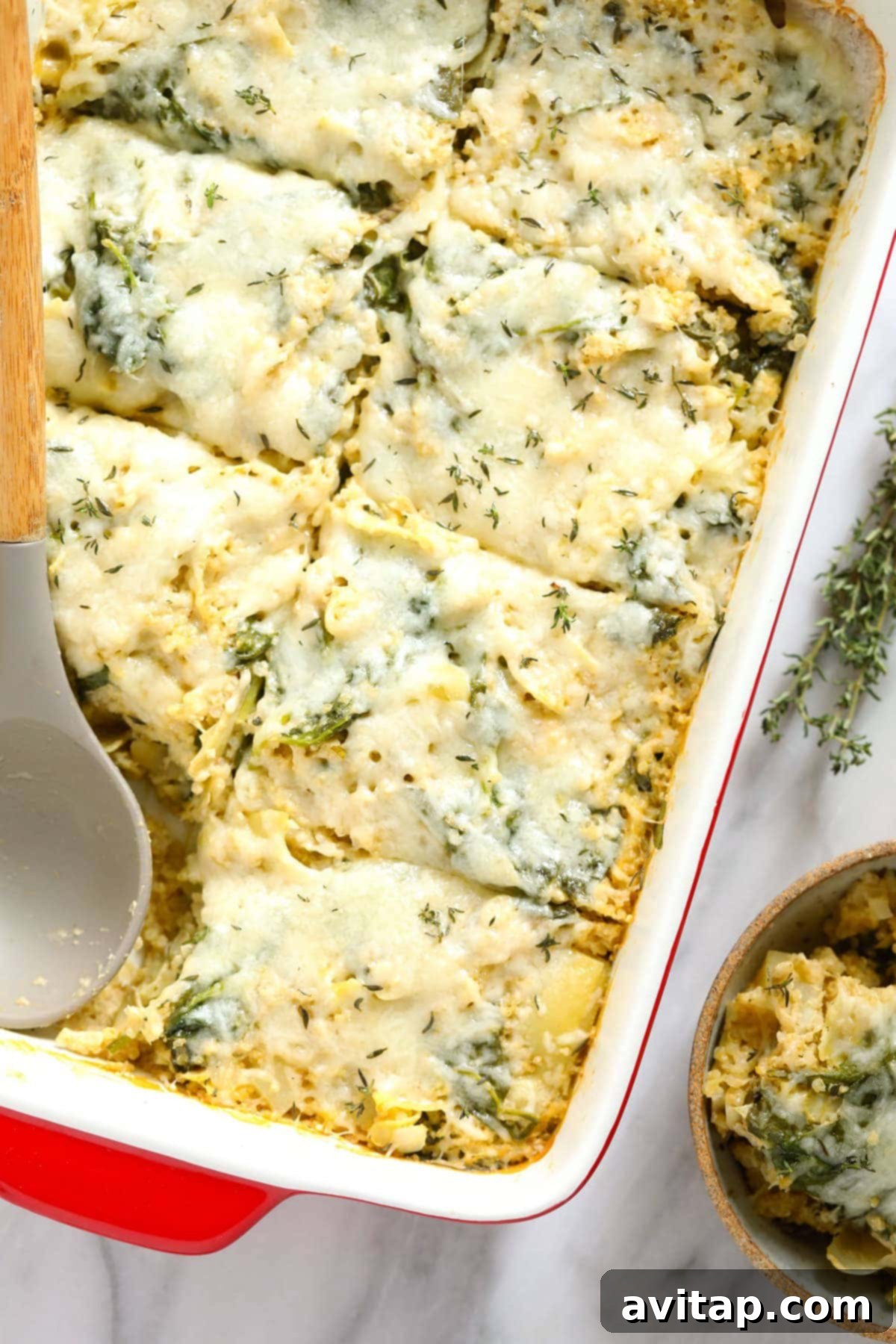 Baked spinach artichoke quinoa casserole, topped with melted cheese and fresh thyme for garnish.