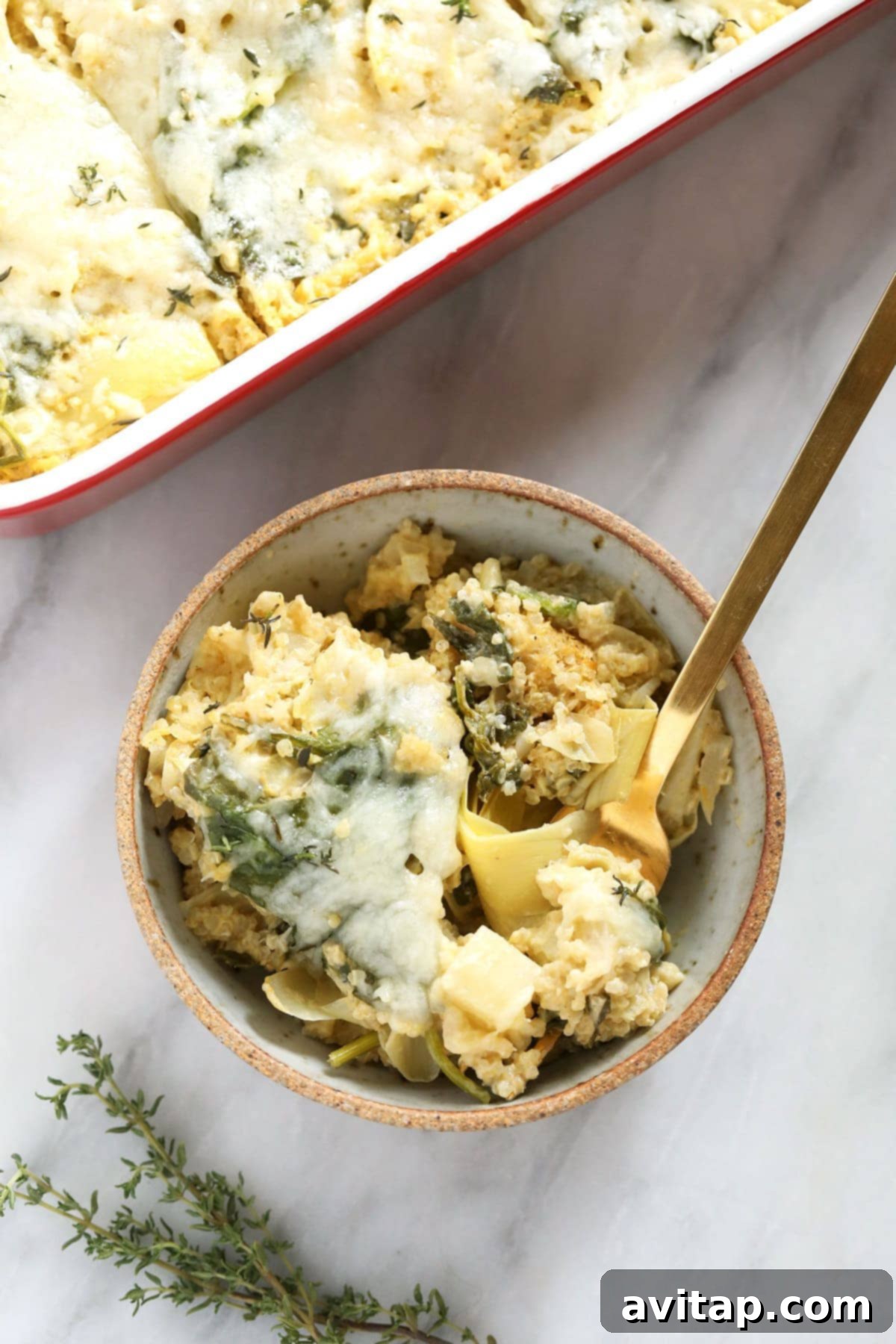 Close-up of the creamy spinach artichoke quinoa casserole, showing the cooked quinoa, spinach, artichokes, and diced potatoes.