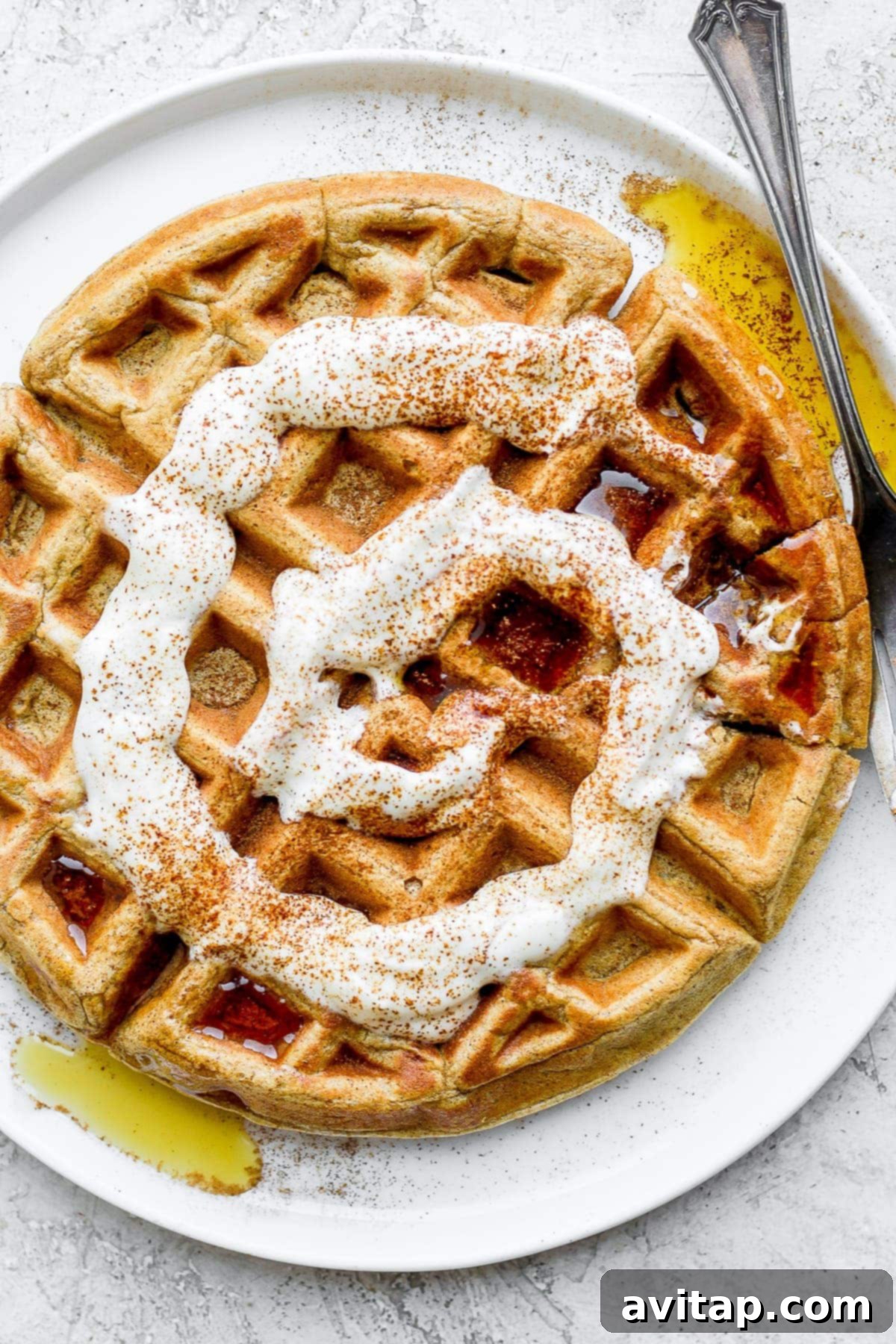 Cinnamon Swirl Waffles 6 cinnamon roll waffle on a plate with maple syrup and a cream cheese drizzle