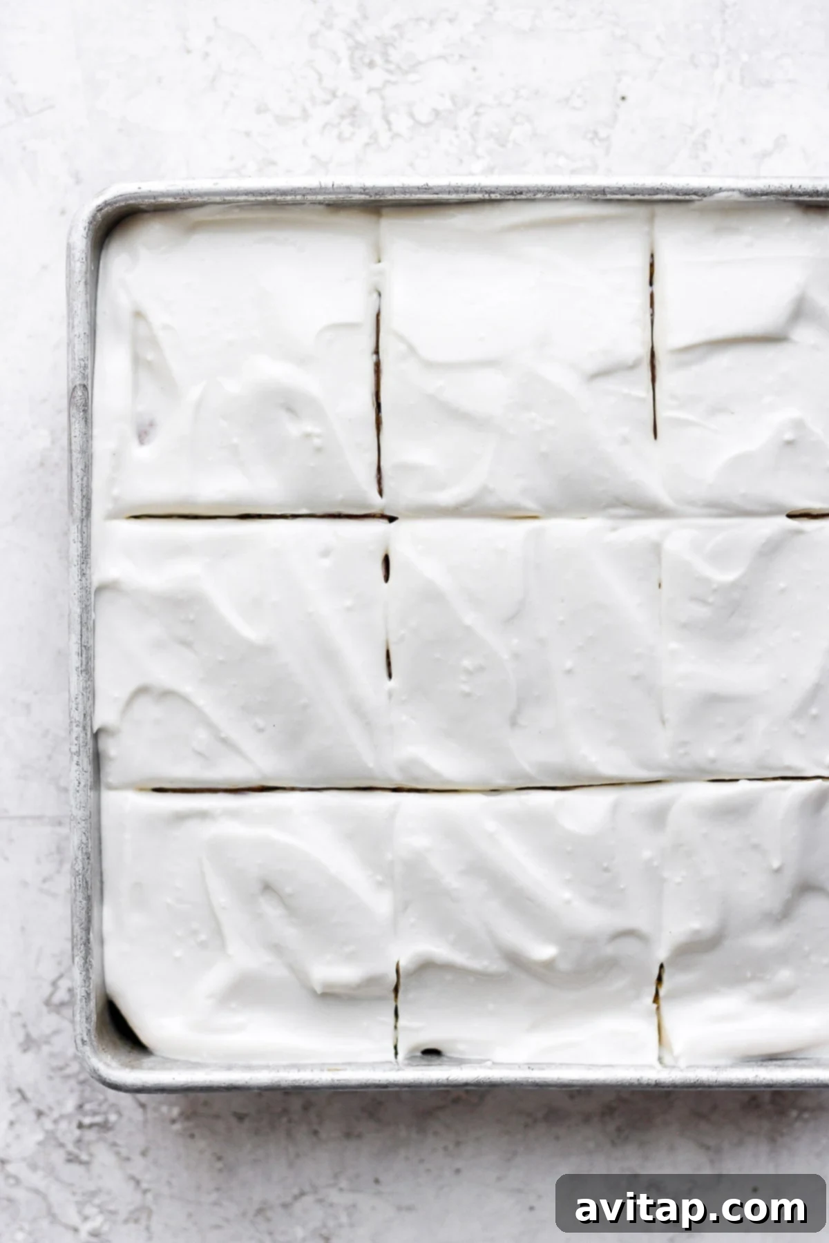 A beautifully frosted pumpkin sheet cake with a generous layer of creamy white cream cheese frosting.