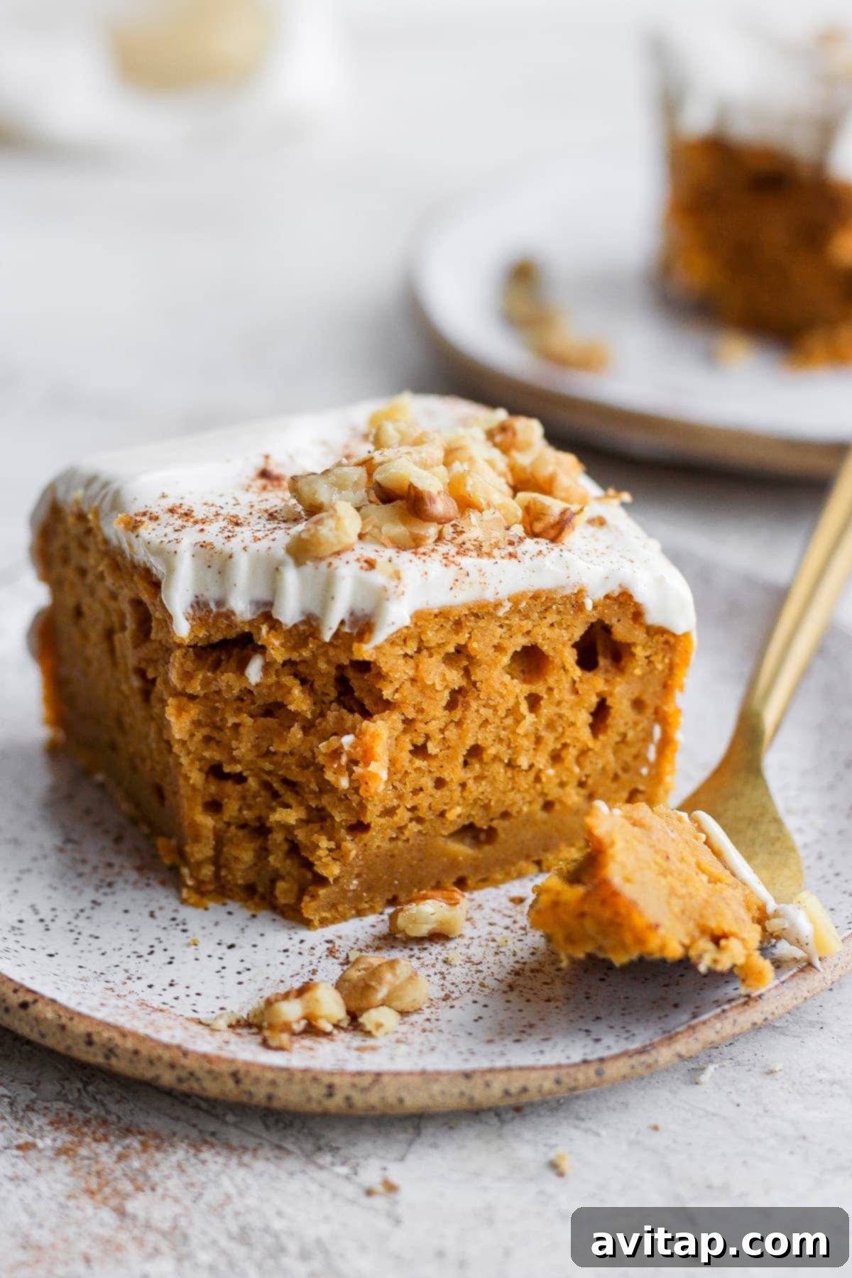 A delightful slice of pumpkin sheet cake with a fork poised for a bite, showcasing the moist interior and creamy frosting.