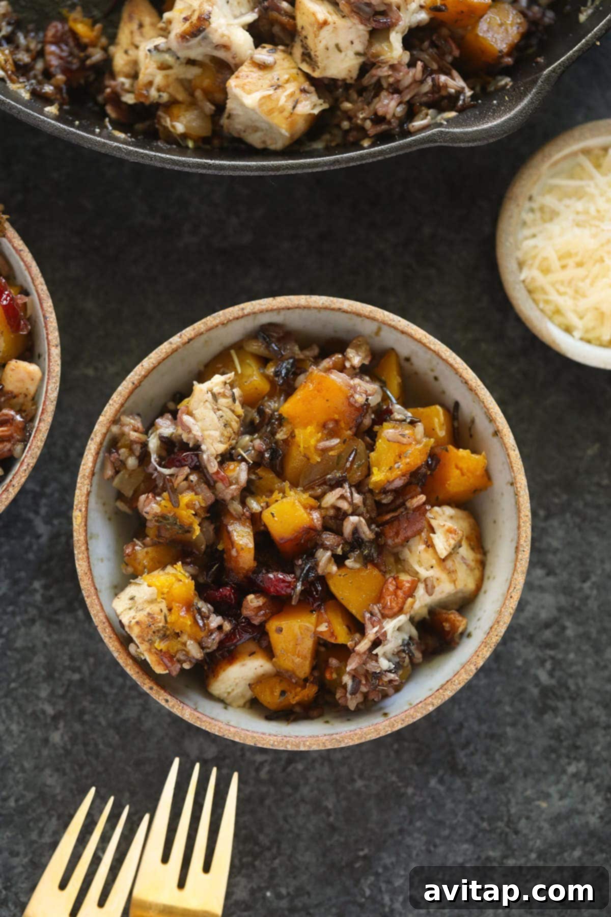 A serving of butternut squash wild rice casserole in a white bowl, garnished with fresh herbs.