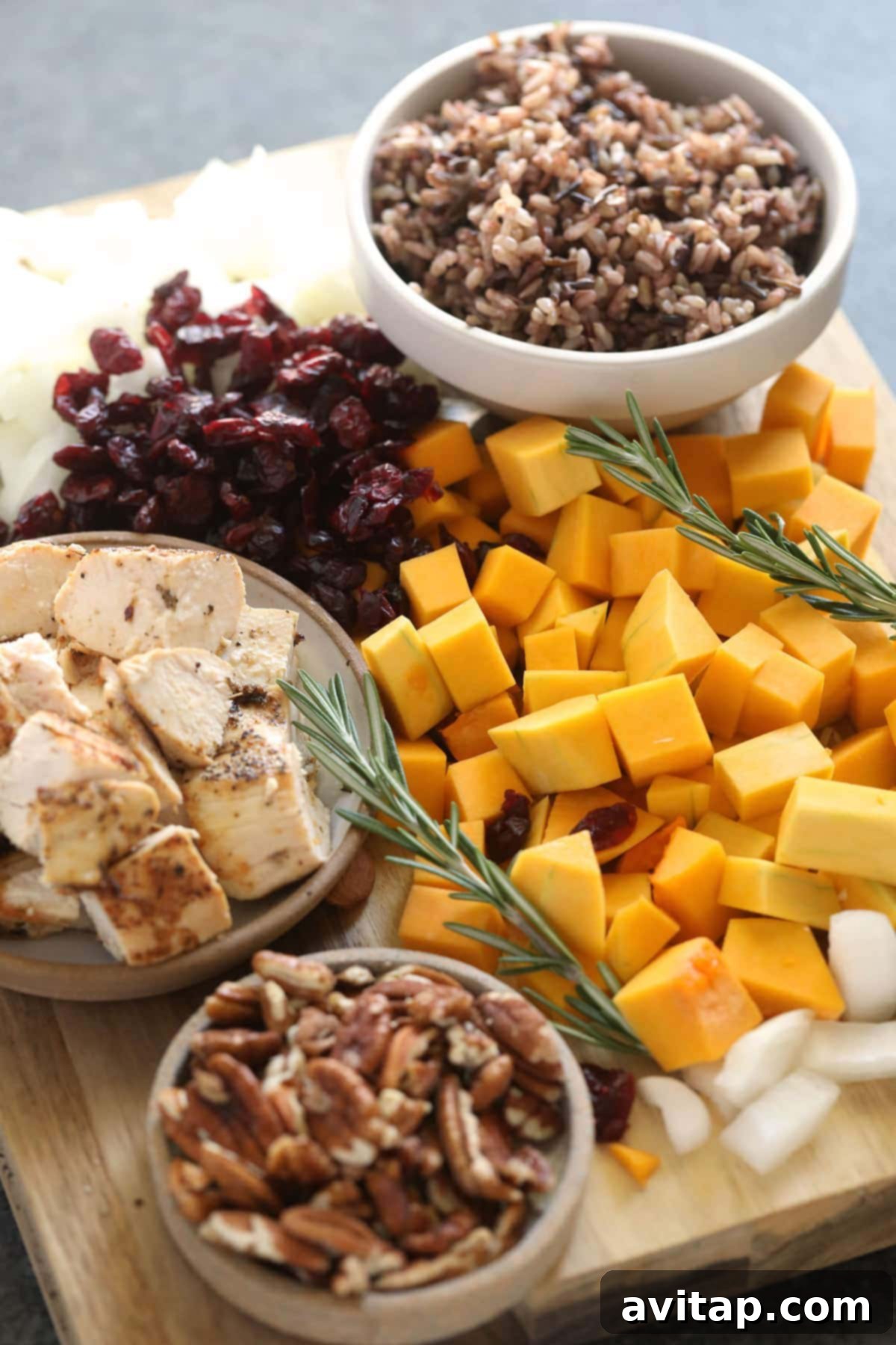 Various ingredients for butternut squash wild rice casserole, including chicken, squash, rice, herbs, and nuts, laid out before mixing.