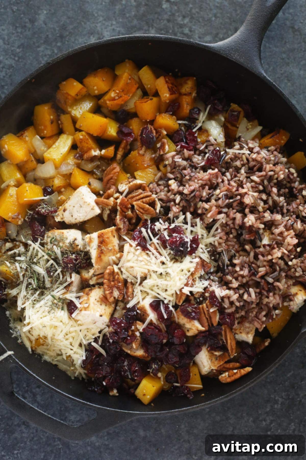 Butternut squash wild rice casserole ingredients mixed in a cast iron pan, ready for baking.