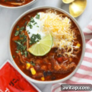 Two bowls of Instant Pot Pork Chili generously topped with shredded cheese and a spoonful of sour cream, ready to serve.